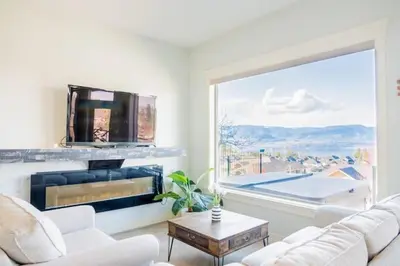 a living room with a fireplace and a large window at Lakeview 2-bed 2-bath Entire Suite near Summerhill Winery in Kelowna