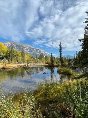 a body of water with trees and mountains in the background at L202 - A Relaxed Vacation- 2BD+2BT, Heated Pool, Hot tubs, Gym, AC, Parkade in Canmore