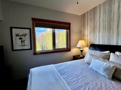 a bedroom with a white bed and a window at L202 - A Relaxed Vacation- 2BD+2BT, Heated Pool, Hot tubs, Gym, AC, Parkade in Canmore
