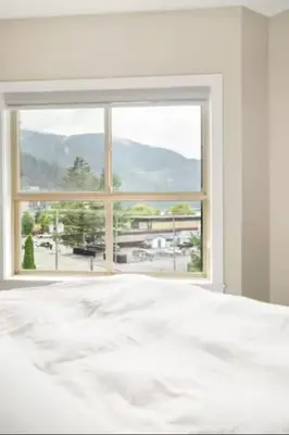 a bedroom with a white bed and a large window at Lakeview Splendor- 7BR Penthouse Bliss Combo unit in Harrison Hot Springs