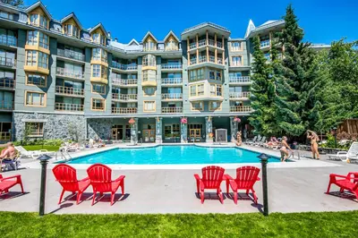 a large apartment building with a pool and red chairs at Cascade Lodge in Whistler
