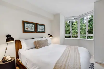 a bedroom with a white bed and two windows at Cascade Lodge in Whistler