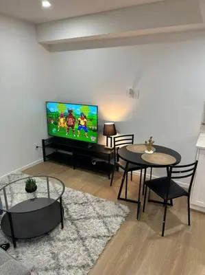 a living room with two tables and a flat screen tv at Guest suite in Southwest Calgary in Calgary