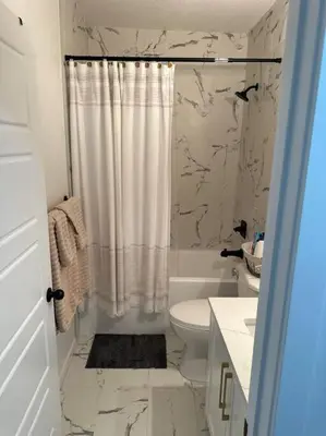 a white bathroom with a shower curtain and a toilet at Guest suite in Southwest Calgary in Calgary