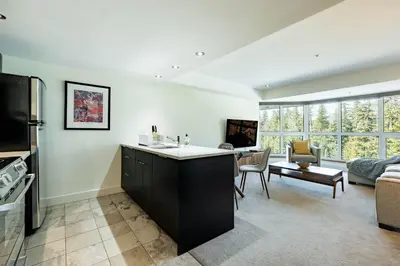 a kitchen and living room with a large window at Le Chamois by Outpost Whistler in Whistler