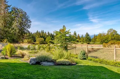 a garden with grass and rocks and a fence at The Nest in Lantzville