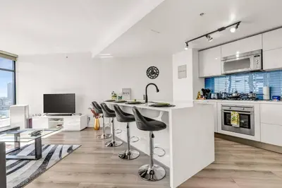 a kitchen with white cabinets and a bar with stools at Central Luxury Apartment with Best City Views! in Vancouver
