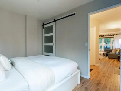 a bedroom with a white bed and a sliding glass door at Ski nest 5m to Creekside Gondola in Whistler