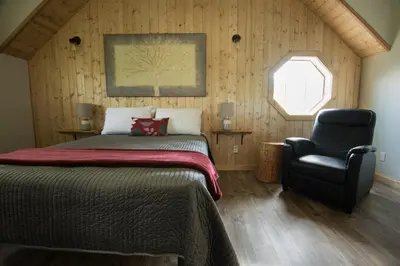 a bedroom with a bed and a chair at Cabins West in Ucluelet