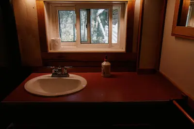 a bathroom sink with a window and a soap bottle at Rustic Beaverfoot Lodge in Parson