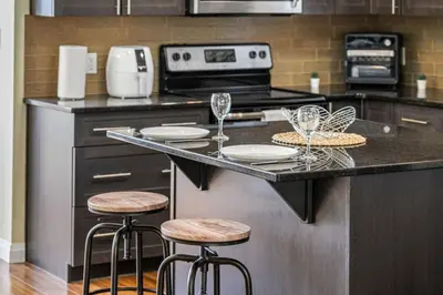 a kitchen with a counter with two stools and a stove at 5 Bedroom House in McConachie, Near Anthony Henday, Sleeps 12, Backyard, Netflix, Free Parking in Edmonton