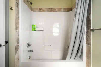 a bathroom with a bath tub with a shower curtain at 5 Bedroom House in McConachie, Near Anthony Henday, Sleeps 12, Backyard, Netflix, Free Parking in Edmonton