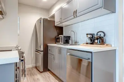 a kitchen with white cabinets and a stainless steel refrigerator at 1Bd Unit In the heart of Whistler Village in Whistler