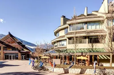 a large building with tables and umbrellas in front of it at 1Bd Unit In the heart of Whistler Village in Whistler
