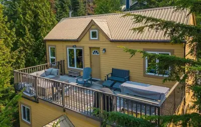 a house with a deck with two blue chairs at 1BR plus Loft in Gondola Village, Creekside, Amazing Patio with Views, Near Gondola, Free Parking in Whistler
