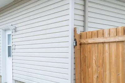 a wooden fence next to a house with a door at Cozy Suite - Walk to West Ed Mall in Edmonton