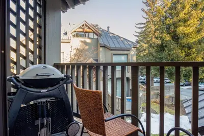 a grill and a chair on a porch at 1BR plus Two Dens in The Gables, Epic Location Near Gondolas, Private Balcony, Fireplace, Parking in Whistler