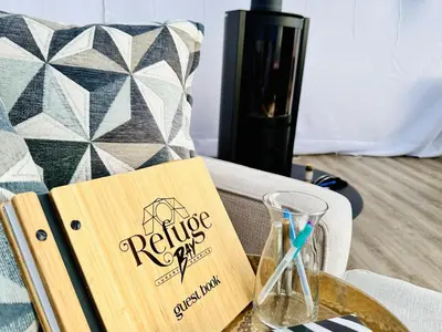 a book on a table next to a wine glass at Refuge Bay's Aer XL Dome Luxury Off Grid Escape in Cherhill