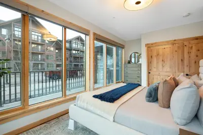 a bedroom with a bed and large windows at Timberstone Condo by Canadian Rockies Vacation Rentals in Canmore