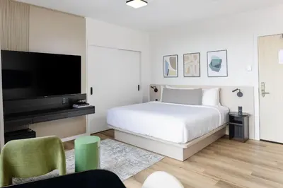 a white bedroom with a bed and a flat screen tv at Smithe House in Vancouver