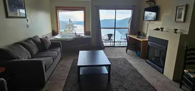 a living room with a couch and a table and a fireplace at Moon Water Lodge in Malahat