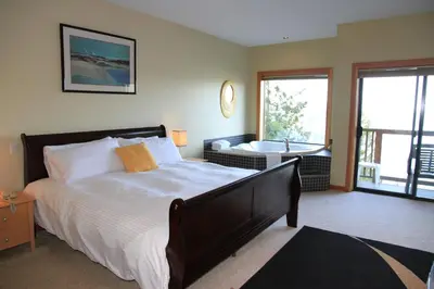 a bedroom with a large bed and a bath tub at Moon Water Lodge in Malahat