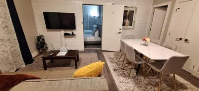a living room with a dining table and a television at Two Bedroom Suite with AC, Sleeps 8- Welcome Snacks and Drinks Included in Langford