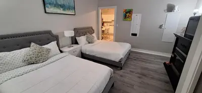 a small bedroom with two beds and a television at Two Bedroom Suite with AC, Sleeps 8- Welcome Snacks and Drinks Included in Langford