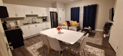 a kitchen and living room with a white table and chairs at Two Bedroom Suite with AC, Sleeps 8- Welcome Snacks and Drinks Included in Langford