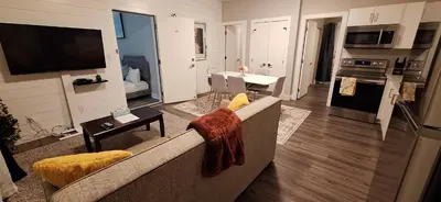 a living room with a couch and a kitchen at Two Bedroom Suite with AC, Sleeps 8- Welcome Snacks and Drinks Included in Langford