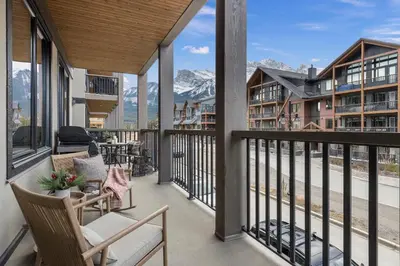 a balcony with chairs and a view of mountains at New Spacious Mountain View Condo in Canmore With Hot Tub, Park Pass, Prime Location in Canmore
