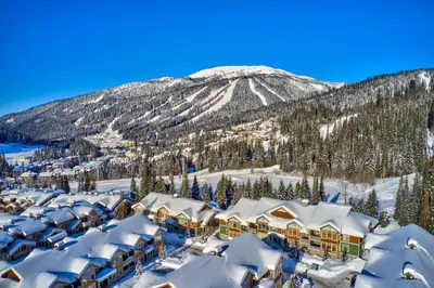a resort covered in snow with a mountain in the background at Settlers Crossing #35 condo in Sun Peaks