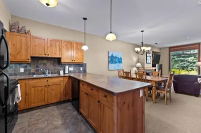 a kitchen with wooden cabinets and a dining room at Settlers Crossing #35 condo in Sun Peaks