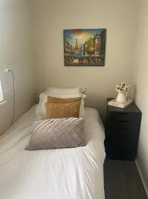 a bedroom with a white bed with a picture on the wall at Quiet-comfy 4 bedroom house on a quiet tree lined street in Kitsilano in Vancouver