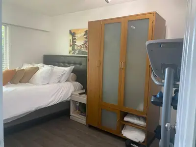 a bedroom with a bed with white sheets and a cabinet at Quiet-comfy 4 bedroom house on a quiet tree lined street in Kitsilano in Vancouver