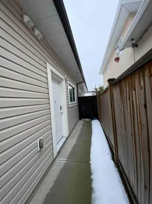 a snow covered sidewalk next to a house with a door at Two Bedroom Suite Burnaby Metrotown in Burnaby