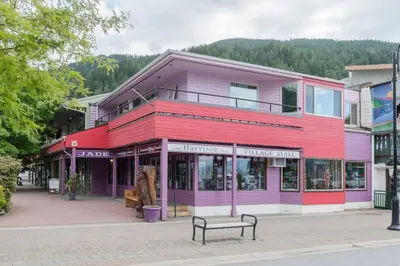 a red and purple building on a street with a bench at Brand New Penthouse with Lake and Mtn Views in Harrison Hot Springs