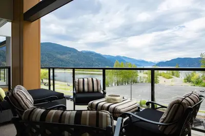 a living room with chairs and a large window at Brand New Penthouse with Lake and Mtn Views in Harrison Hot Springs