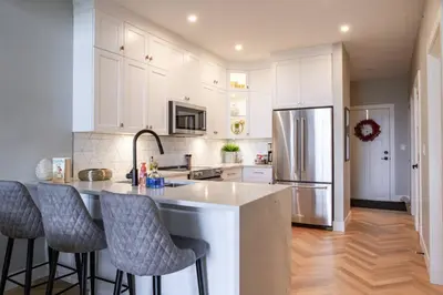 a kitchen with white cabinets and a kitchen island with bar stools at Brand New Penthouse with Lake and Mtn Views in Harrison Hot Springs
