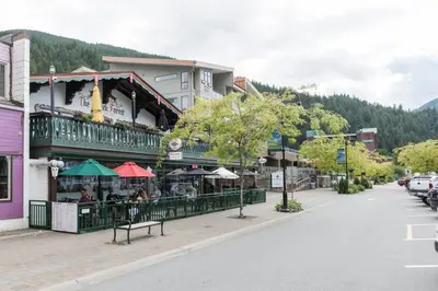 a town street with a building with tables and umbrellas at New 1 Bed Condo with Mtn Views in Harrison Hot Springs