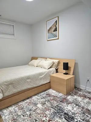 a bedroom with a bed and a table with a lamp at Cozy 2 bedrooms and 1 bath for 4 guests! in Calgary