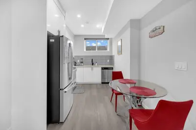 a kitchen with a glass table and red chairs at Modern & Spacious Guest Suite in Calgary