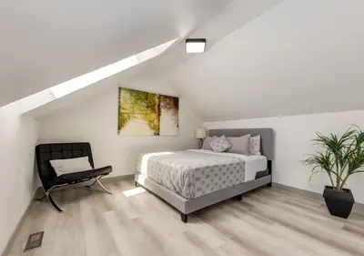 a white bedroom with a bed and a chair at Newly Renovated Vacation Home w/ Hot Tub & Garage in Calgary