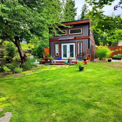 a tiny house in a yard with green grass at Tiny House with Hot Tub, close to golf and skiing!! in Oyster Bay