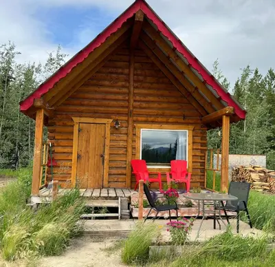 a log cabin with red chairs and a table at Dry Log Cabin with Mountain Views in Upper Laberge