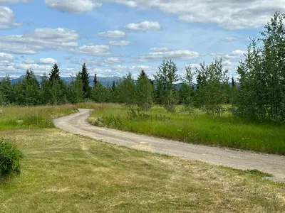 a dirt road in the middle of a field at Dry Log Cabin with Mountain Views in Upper Laberge