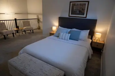 a bedroom with a large white bed and two chairs at Family Home Retreat - 9 mins to WEM - Vintage Arcade-Ping Pong -Air Conditioning in Edmonton