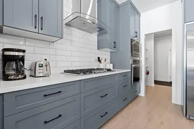 a kitchen with white cabinets and a stove top oven at Family Home Retreat - 9 mins to WEM - Vintage Arcade-Ping Pong -Air Conditioning in Edmonton