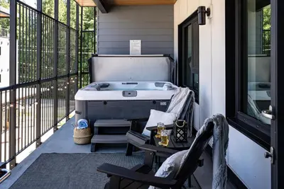 a hot tub on a porch with a table and chairs at Birdies and Bears by Revelstoke Vacations in Revelstoke