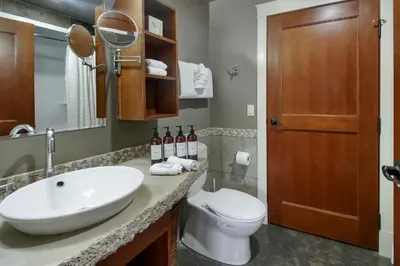 a bathroom with a sink and a toilet and a mirror at Marvellous Mountain Condo- Pets - Pool & Hot Tub managed by Little Sister Getaways in Canmore